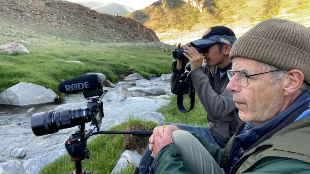 Two men with cameras watching birds by a river in Mongolia